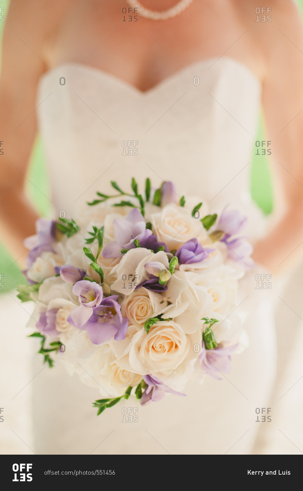 Bride holding bouquet of white roses and purple flowers
