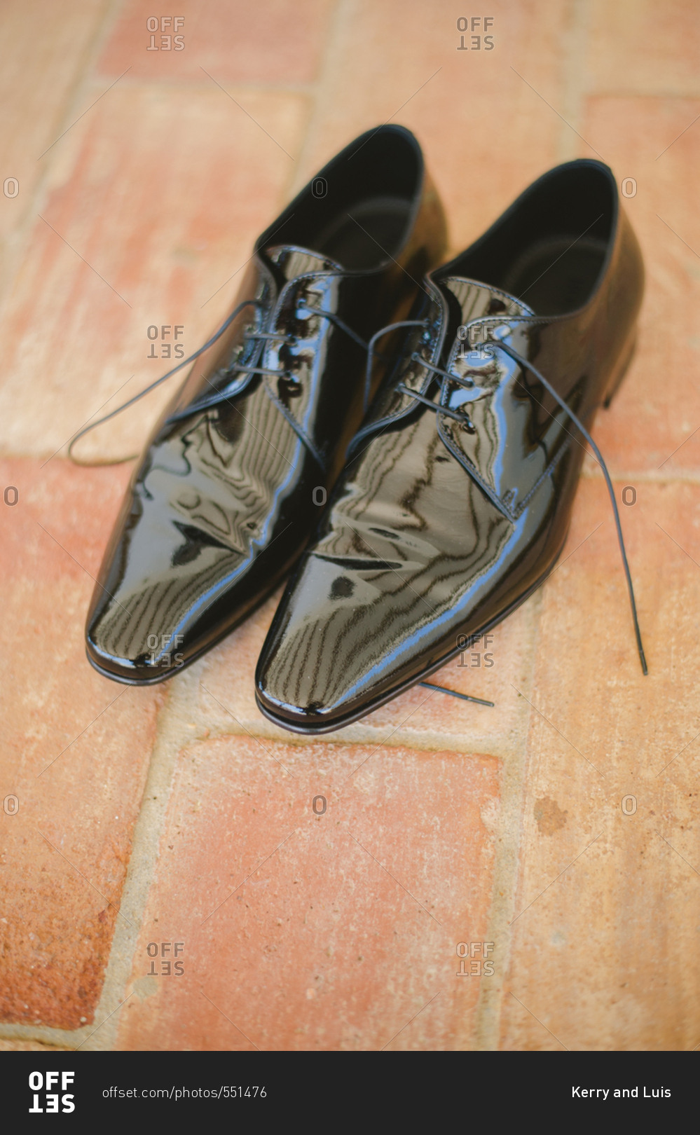 Shiny patent leather men's dress shoes on brick floor stock photo - OFFSET