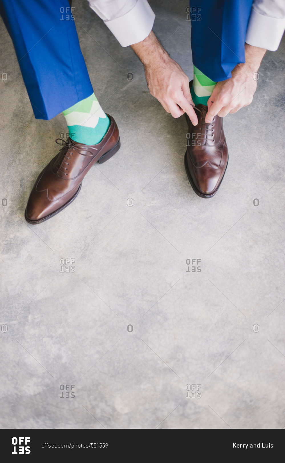Groom in blue suit pants putting on brown leather shoes