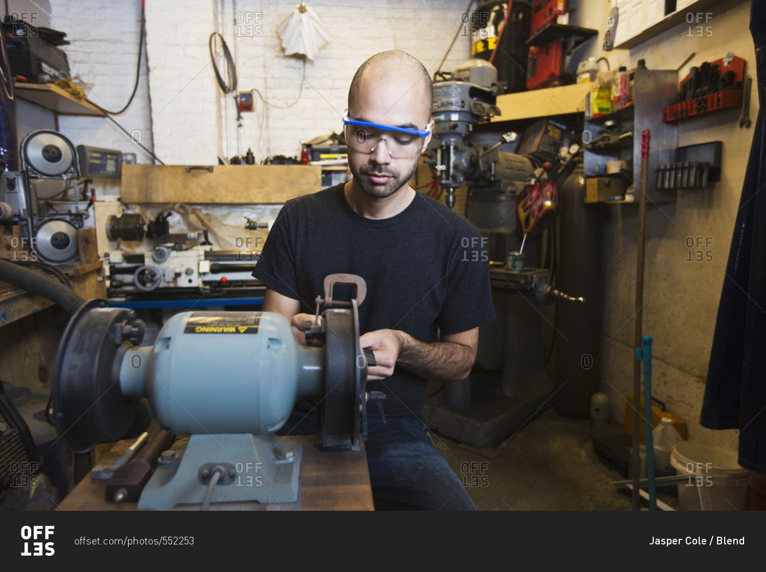 Mixed Race man using machinery in workshop