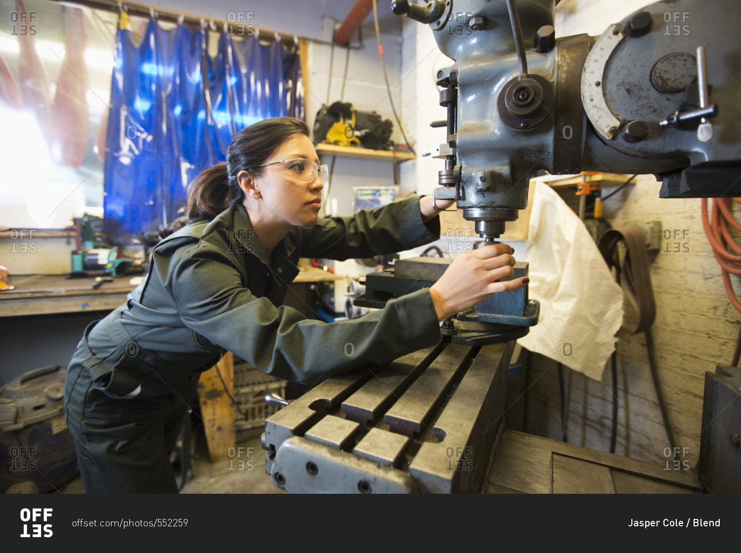 Mixed Race woman using machinery in workshop