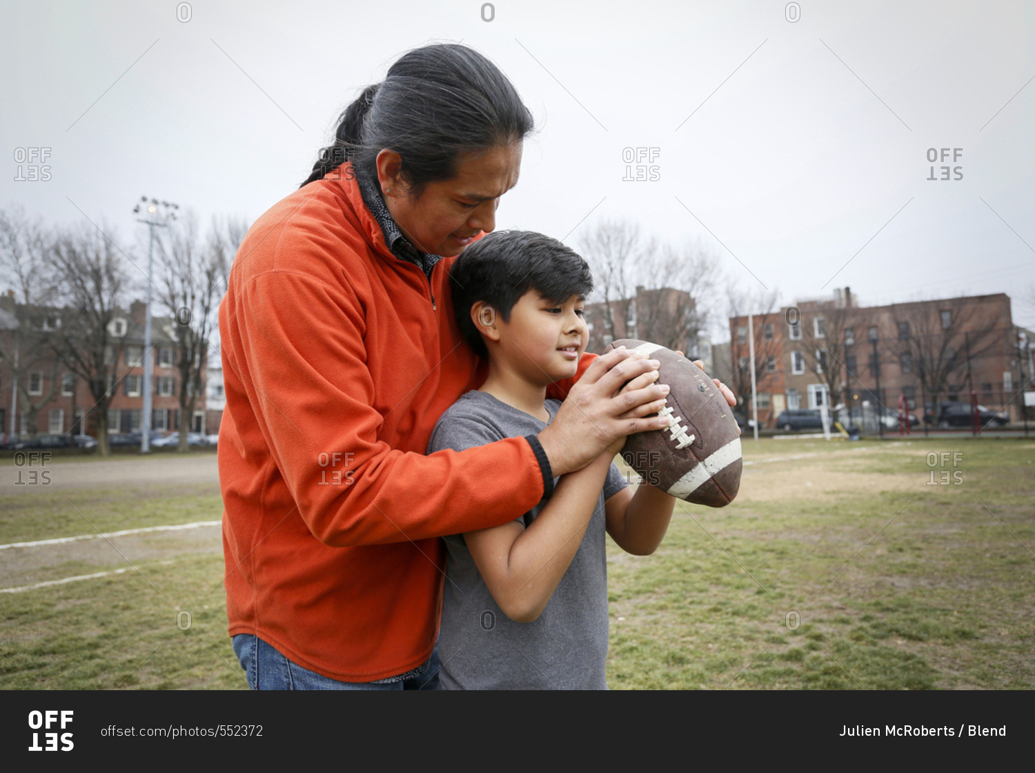 Native American father teaching son to throw football