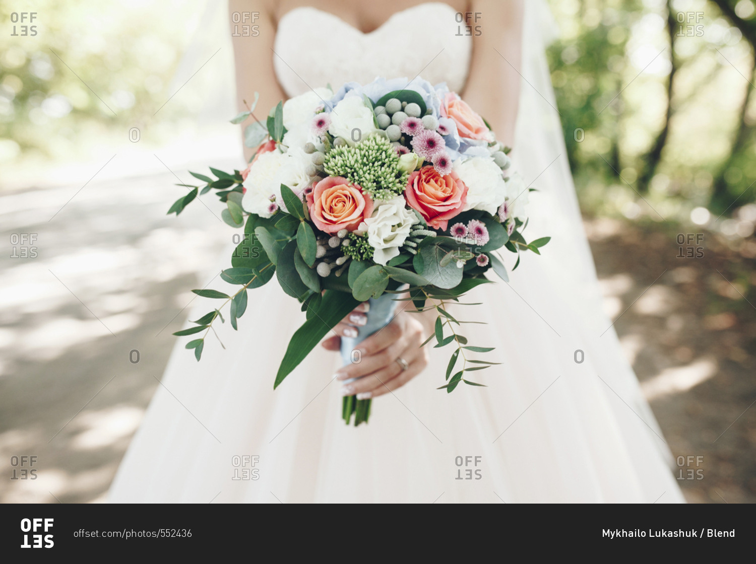 Caucasian bride holding bouquet of flowers outdoors