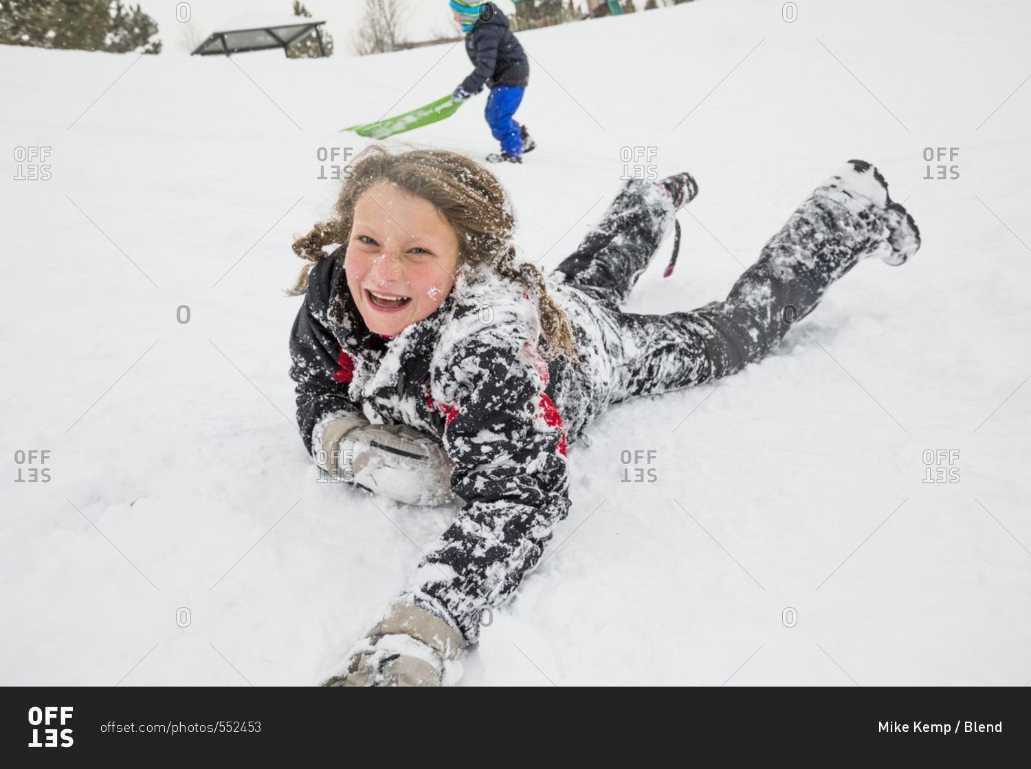 Laughing girl laying in snow in winter