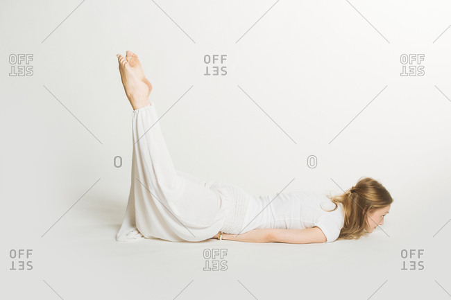 Woman lying on her stomach in a yoga pose lifting both legs into the air