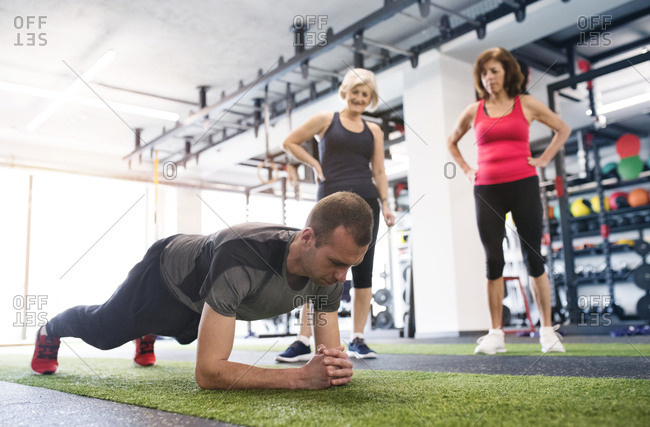 Large group of women training in gym with male trainer, in rows doing push  ups stock photo