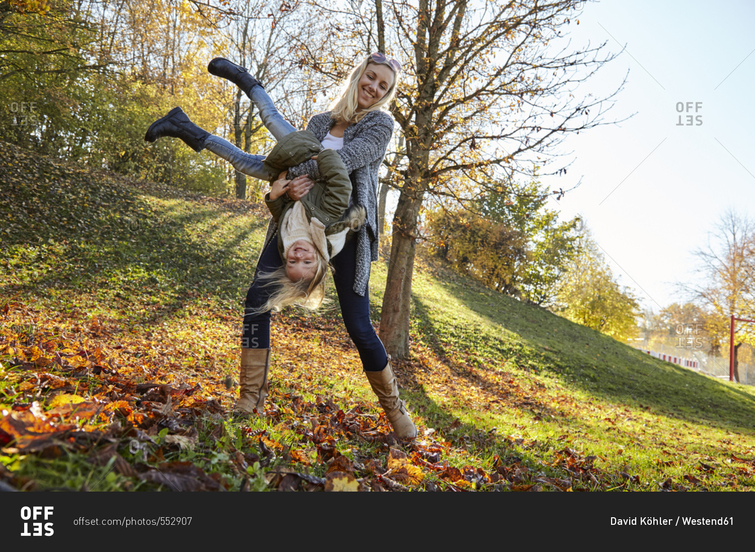 Mother and daughter playing in park in autumn