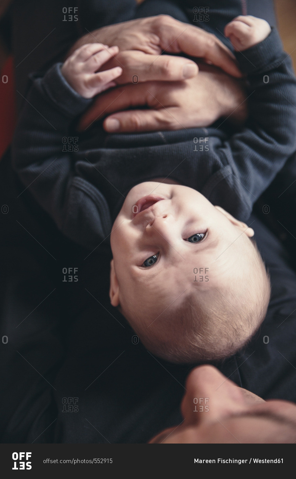Three-month-old baby being held by father as seen from above