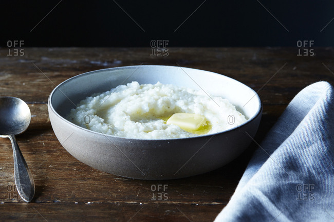 Dish of hot buttered grits with spoon
