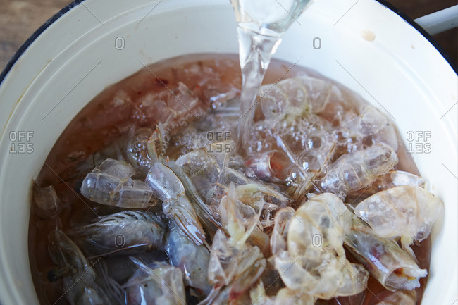 Pouring water into pot of shrimp shells to make stock