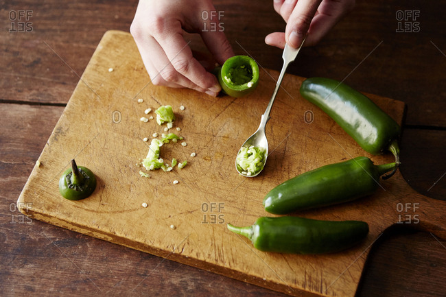 Using a small spoon to scoop seeds from jalapeno