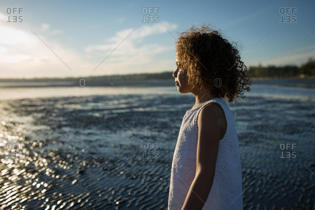 Girl staring out to sunlit ocean
