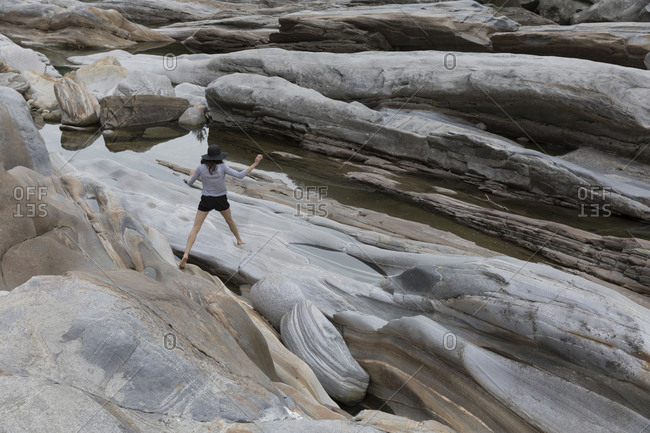 Rear view of female hiker walking on rocks