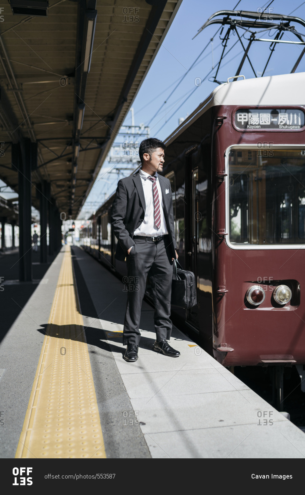 Full length of thoughtful businessman standing by train on railroad station platform