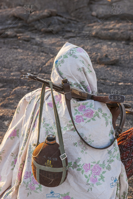 Tigray, Ethiopia - December 3, 2010: A person wrapped in a blanket, carrying a canteen on a riffle while climbing of volcano Erta Ale