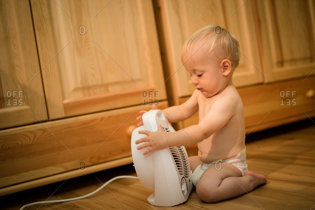 Baby boy tying to operate mini fan heater