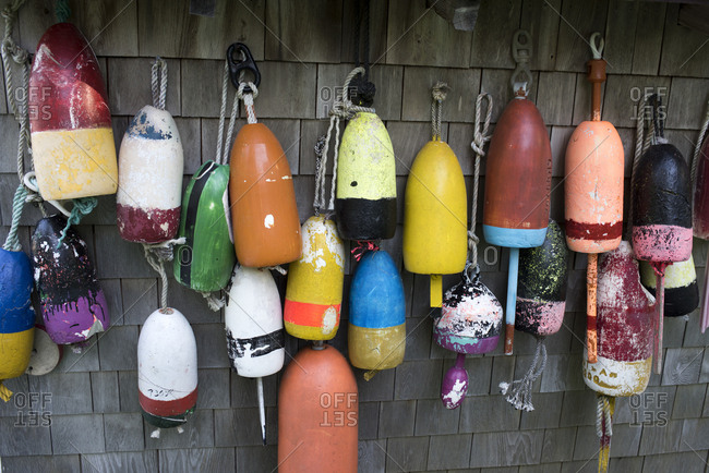 Variety of colorful fishing buoys hanging outside of cedar sided building in Cushing, Maine
