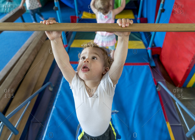 Boy hanging from bar in children's gym