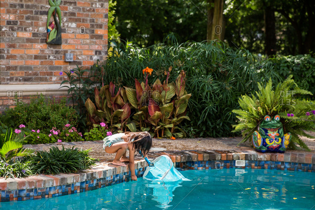 Girl reaching into the water of swimming pool