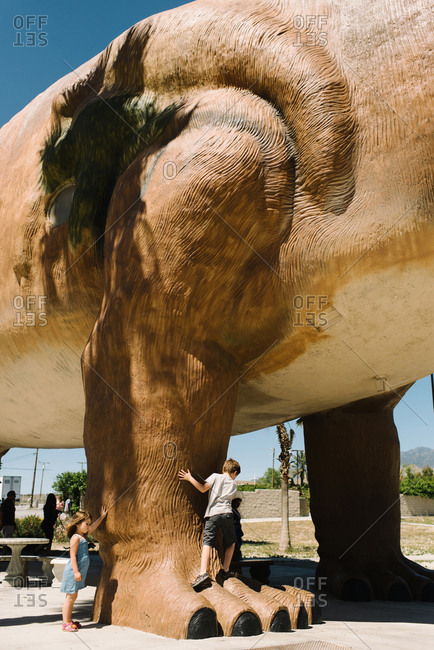 Cabazon, California - March 29, 2017: Kids climbing a dinosaur statue
