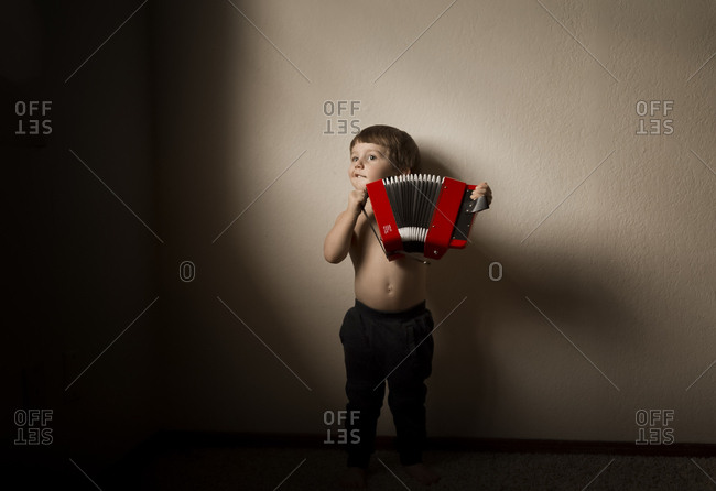 Little boy playing with a toy accordion