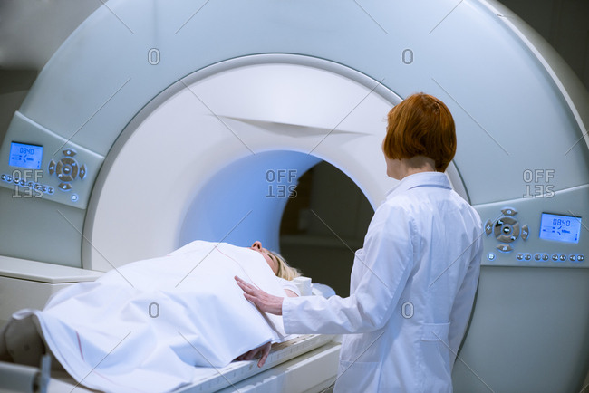 Female doctor preparing patient for magnetic resonance imaging