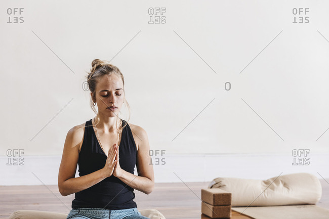 Relaxed young woman sitting in prayer position at yoga studio