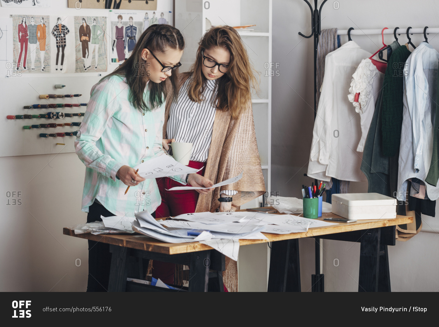 Fashion designer and female trainee looking at sketch at workbench in