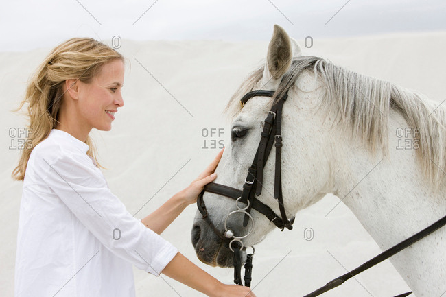 Blonde woman with horse on the beach
