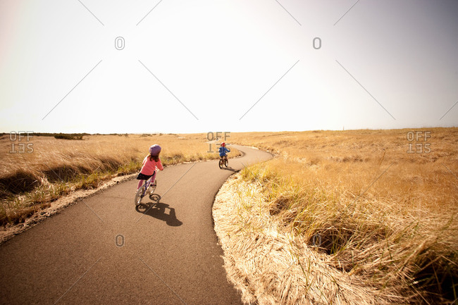 Two children cycling along lane