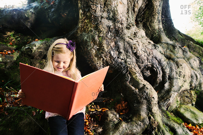 Young girl reading a book in a woodland