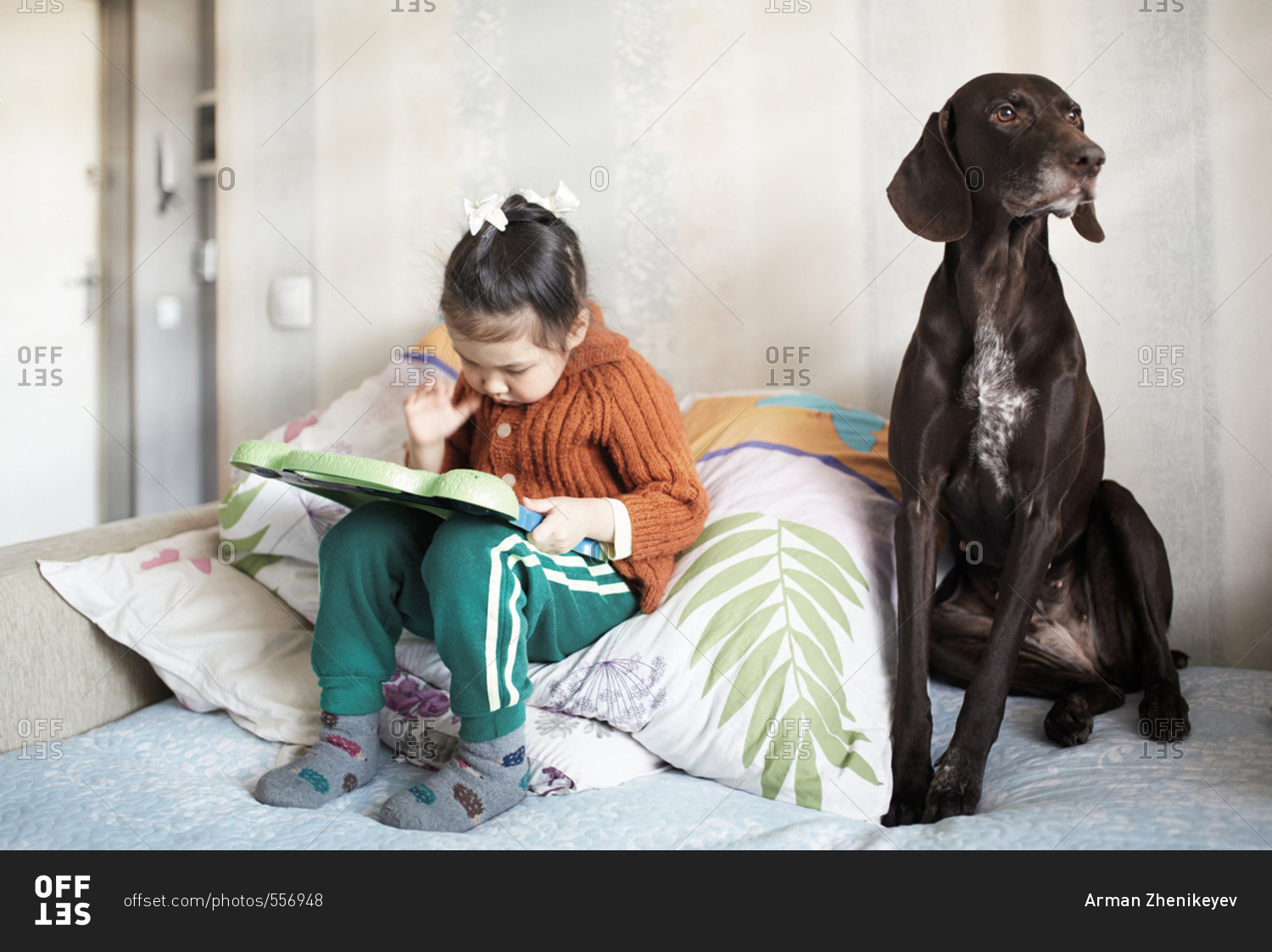 Girl playing interactive game board near to her dog
