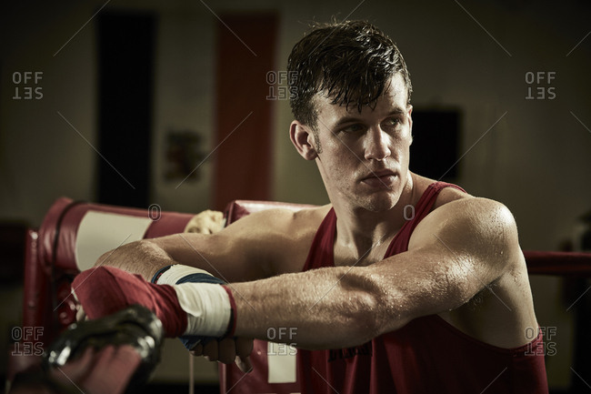 Thoughtful male boxer standing in boxing ring at health club