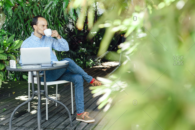 Remote worker man having a cup of coffee on a terrace in Medellin, Colombia