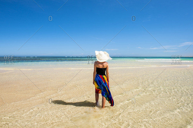 Turquoise Bay, Ningaloo Coast, Exmouth, Western Australia, Australia. Woman with straw hat and colored dress walking on the beach