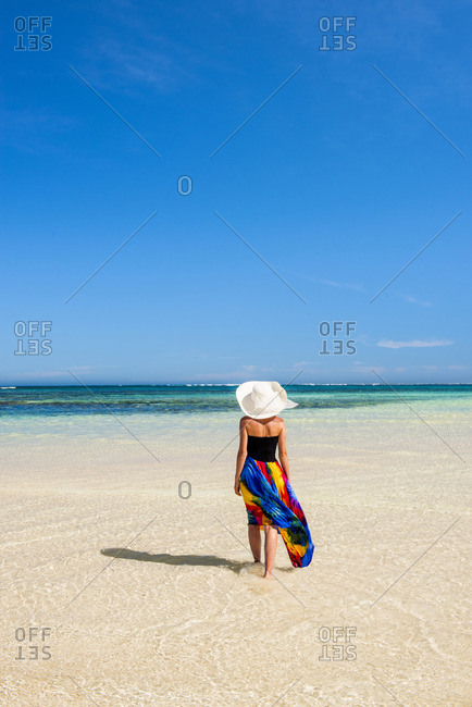 Turquoise Bay, Ningaloo Coast, Exmouth, Western Australia, Australia. Woman with straw hat and colored dress walking on the beach