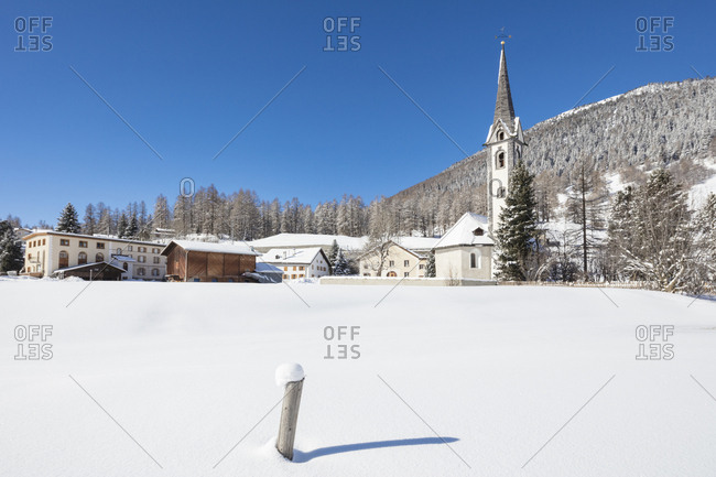 The alpine village covered with snow framed by blue sky, Cinuos, Canton of Graubunden, Engadine, Switzerland, Europe