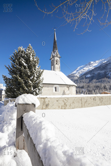 Alpine church covered with snow framed by blue sky, Cinuos, Canton of Graubunden, Engadine, Switzerland, Europe