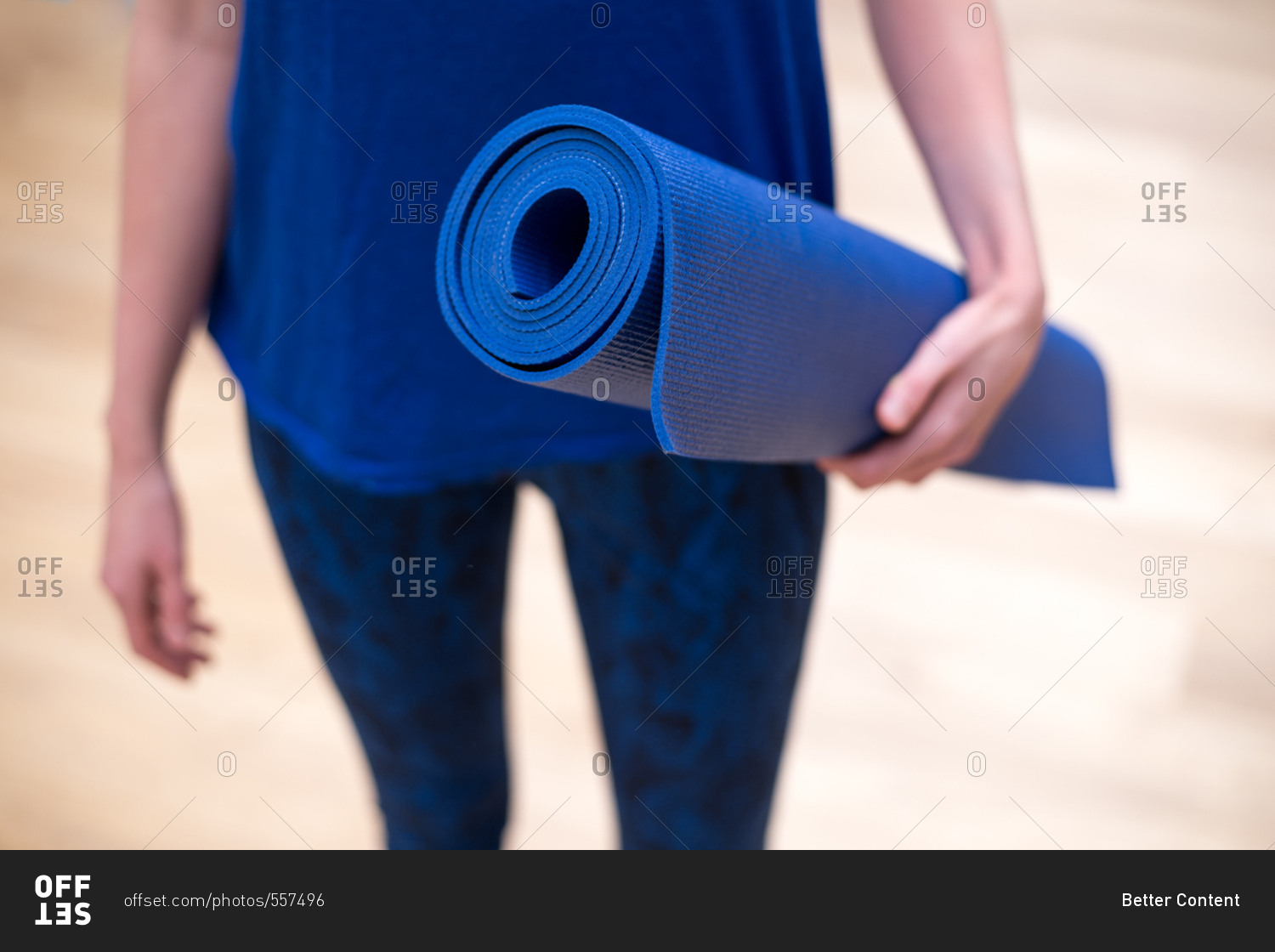 Young woman dressed in blue yoga clothes with a blue yoga mat