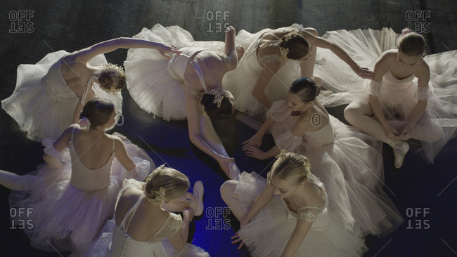 Overhead view of serious ballet dancers in costume stretching backstage during show