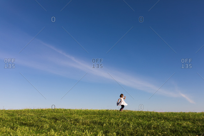 Girl twirling in dress on grassy hill