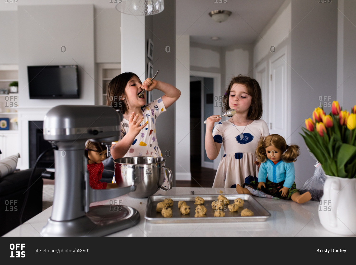 Young girls eating cookie dough in kitchen