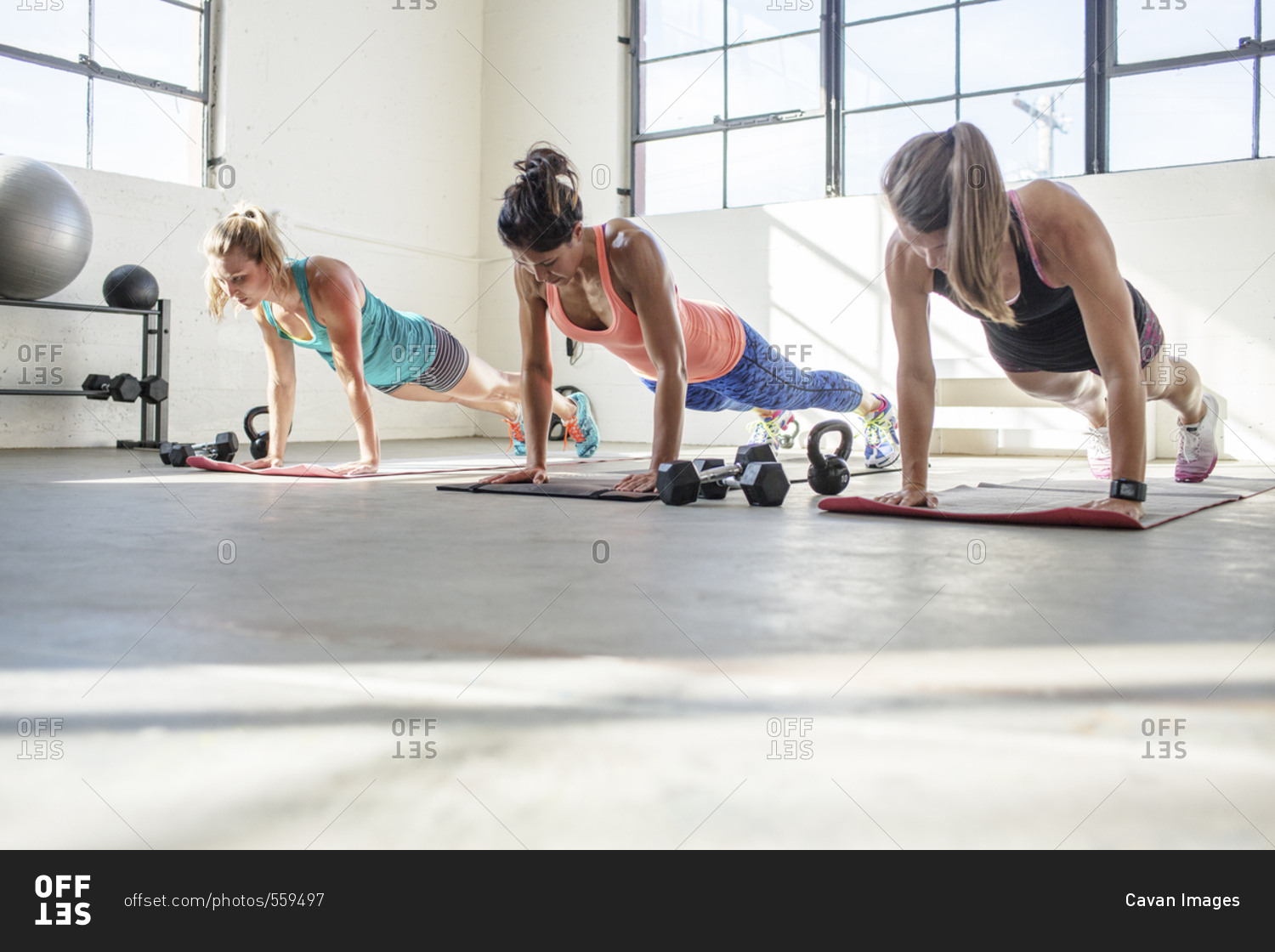 Female athletes doing push-ups on exercise mats in health club