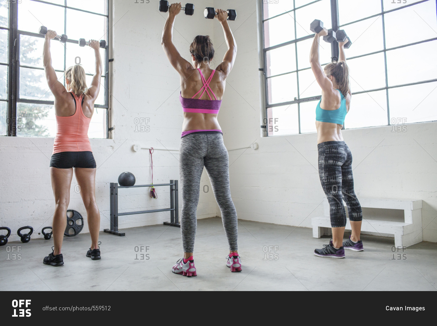 Full length of female athletes lifting dumbbells in health club