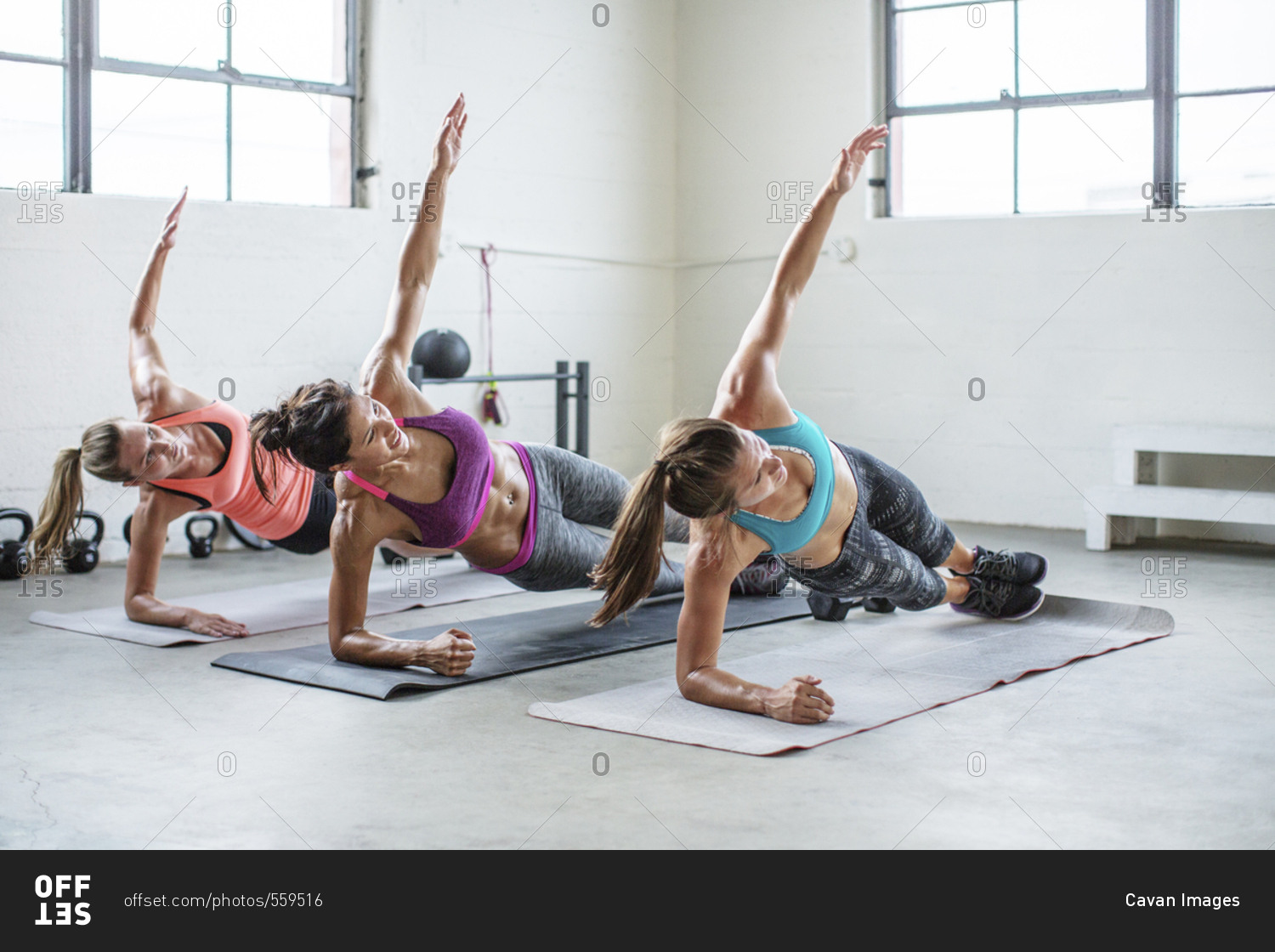 Female athletes doing side plank pose in gym