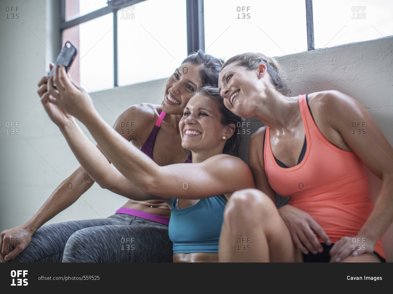 Happy female friends taking selfie through mobile phone in health club