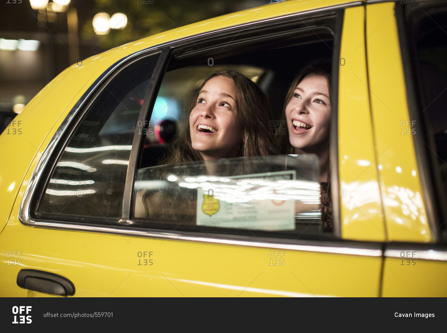 Smiling female friends looking through window while traveling in taxi
