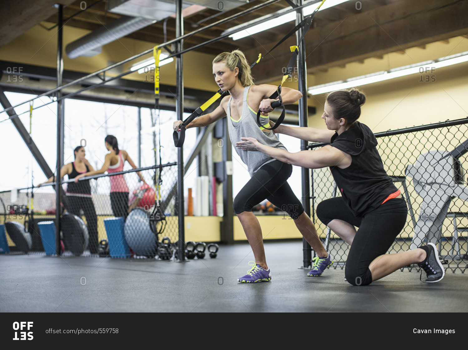 Instructor assisting woman in pulling resistance bands at health club