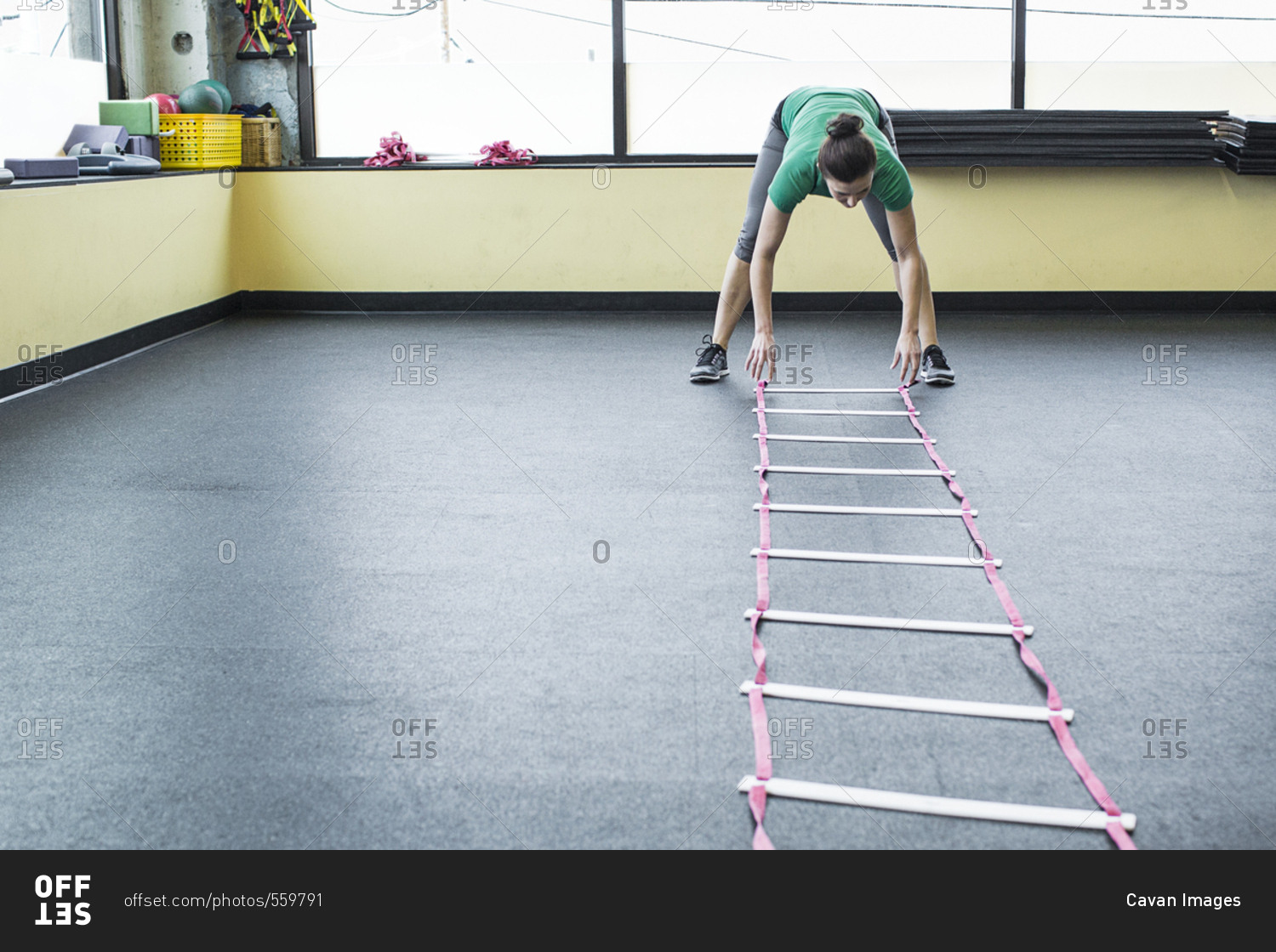Instructor placing agility ladder on floor in gym