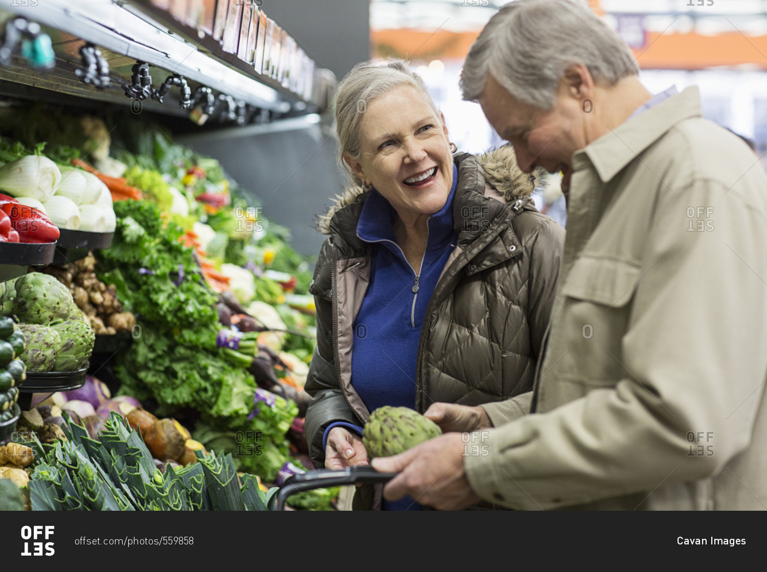 Smiling senior couple shopping for vegetables at supermarket